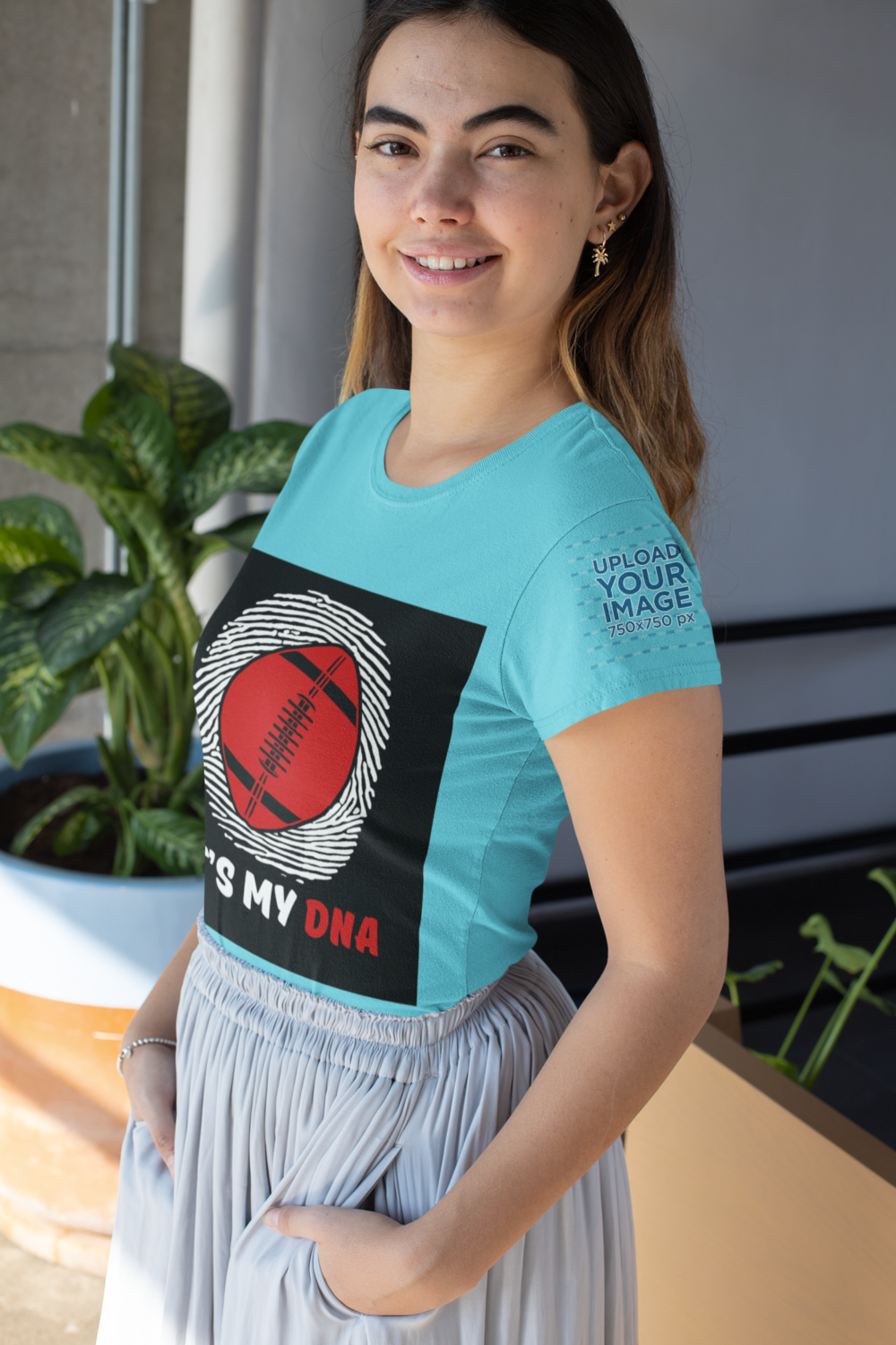 mockup of a woman wearing a t shirt with a customizable sleeve next to a plant 31459 1 1