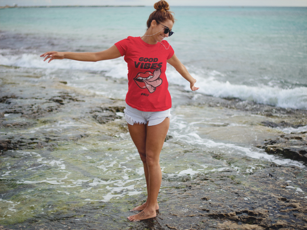 trendy girl at the beach wearing a round neck tee mockup and shorts a12727 1 1067x800 1